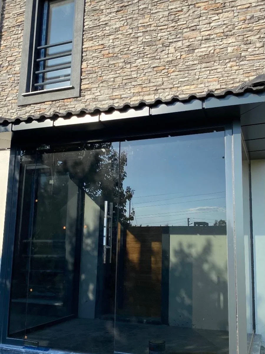 Taş cepheli binada siyah profilli cam kapı ve vitrin uygulaması